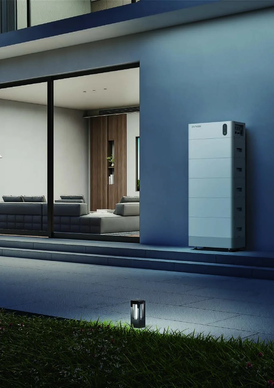 Woning in de avond met een Dyness-thuisbatterij aan de gevel