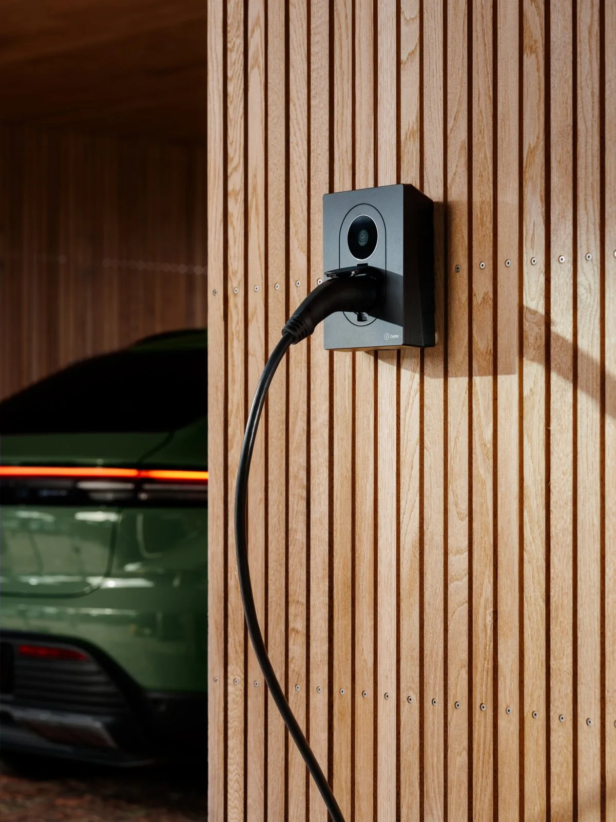Zaptec Go 2 aan een houten gevel met ladende auto